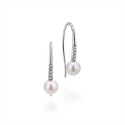 A pair of elegant Gabriel & Co 14K White Gold Diamond and Pearl Fish Wire Drop Earrings, featuring thin, curved hooks adorned with small, sparkling diamonds. Each earring has a single round pearl that hangs delicately at the end. The design is minimalistic and classic.