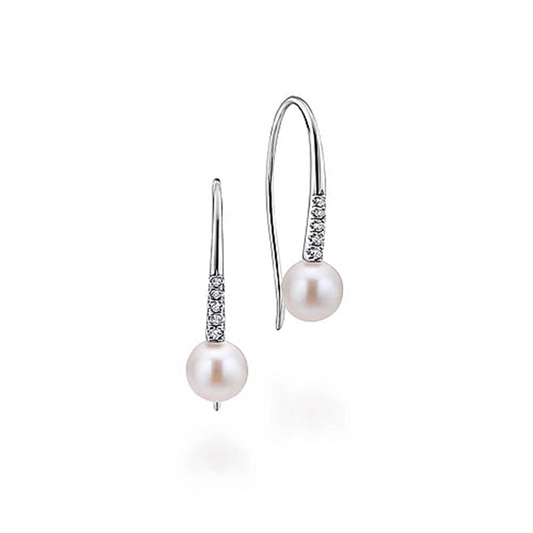 A pair of elegant Gabriel & Co 14K White Gold Diamond and Pearl Fish Wire Drop Earrings, featuring thin, curved hooks adorned with small, sparkling diamonds. Each earring has a single round pearl that hangs delicately at the end. The design is minimalistic and classic.