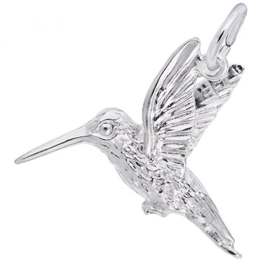 The Hummingbird Charm by Rembrandt Charms, crafted in sterling silver, features intricate detailing on the wings and body. Depicted mid-flight with an outstretched beak and wings flapping upward, it is attached to a small circular loop for adding to a necklace or bracelet.