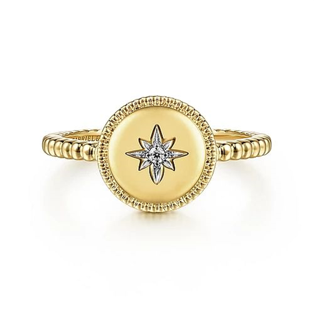The 14K Yellow Gold Round Diamond Star Bujukan Ring from Gabriel & Co features a beaded band with a round, flat top adorned with a starburst design. At the center of the starburst is a small, sparkling round diamond set in 14K Yellow Gold. The edges of the round top are intricately detailed, adding elegance to this exquisite piece from the Bujukan Collection.