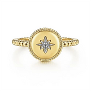 The 14K Yellow Gold Round Diamond Star Bujukan Ring from Gabriel & Co features a beaded band with a round, flat top adorned with a starburst design. At the center of the starburst is a small, sparkling round diamond set in 14K Yellow Gold. The edges of the round top are intricately detailed, adding elegance to this exquisite piece from the Bujukan Collection.
