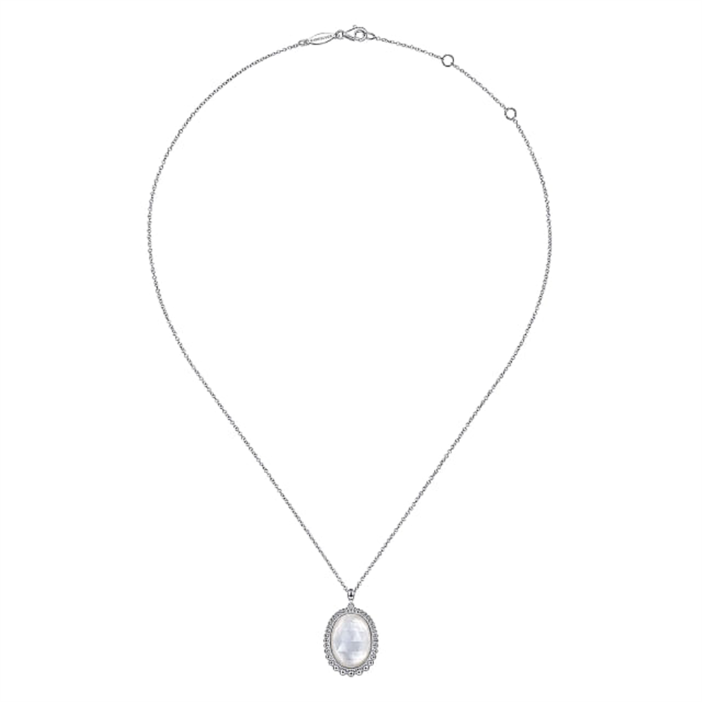 This elegant 925 Sterling Silver Rock Crystal and White MOP Pendant Necklace from Gabriel & Co. showcases a fine chain with a central oval-shaped pendant. The pendant is beautifully adorned with a large, translucent rock crystal surrounded by smaller sparkling stones, and it secures with a simple clasp in the back.