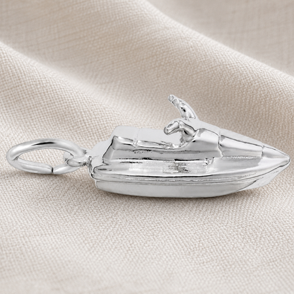 A Rembrandt Charms Jet Ski Charm in sterling silver, featuring a loop for easy attachment, is displayed on a textured beige fabric background—ideal for beach lovers and watersports enthusiasts.