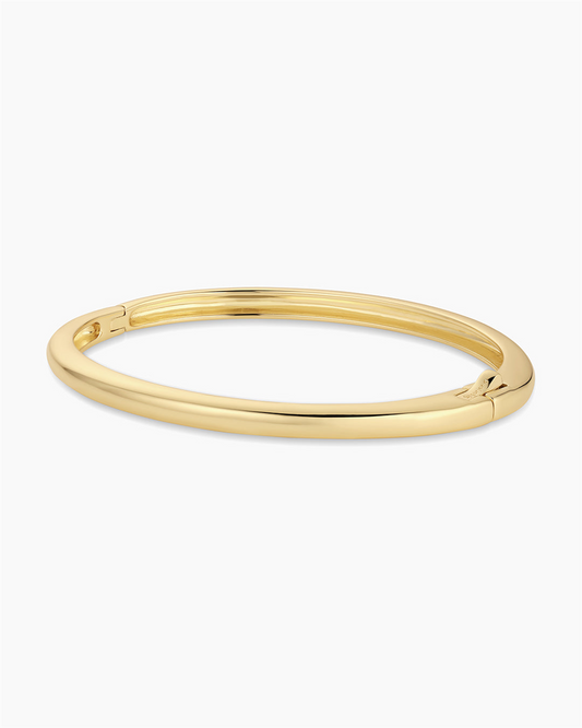 The Gorjana Paseo Cuff is an 18k gold plated bangle bracelet featuring a smooth, oval shape and discreet hinge clasp, shown against a plain white background.