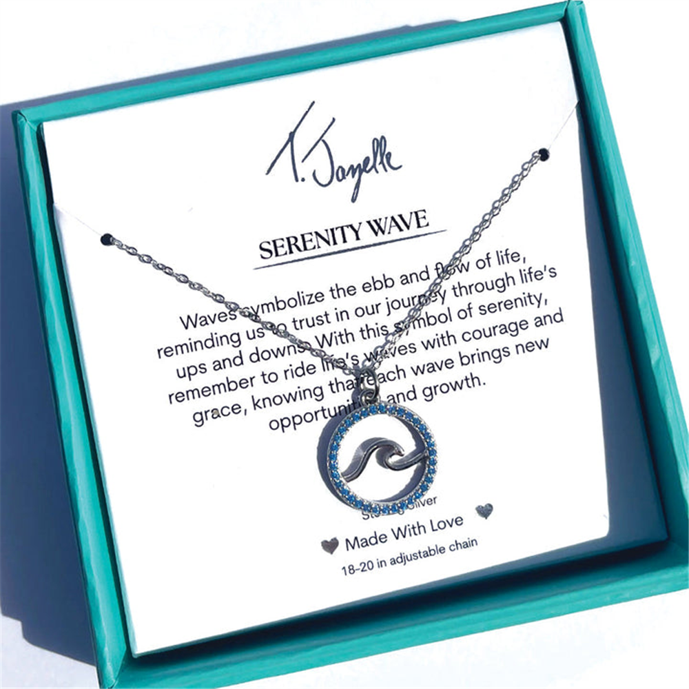 The Serenity Wave Sterling Silver Charm Necklace by T Jazelle features a wave pendant in a turquoise box. The card inside reads "SERENITY WAVE," symbolizing life's journey, and notes the necklace is made with love.