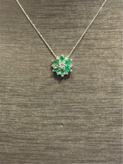 The Ryan Gems Emearald and Diamond Flower Pendant in 14k white gold features emeralds and diamonds, shown on a textured brown surface.