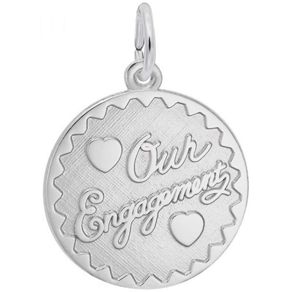 The Engravable Engagement Disc Charm in sterling silver by Rembrandt Charms features a round design with scalloped edges, two heart motifs, and the engraved words “Our Engagement” in elegant cursive—making it a romantic and beautifully personalized engagement keepsake.