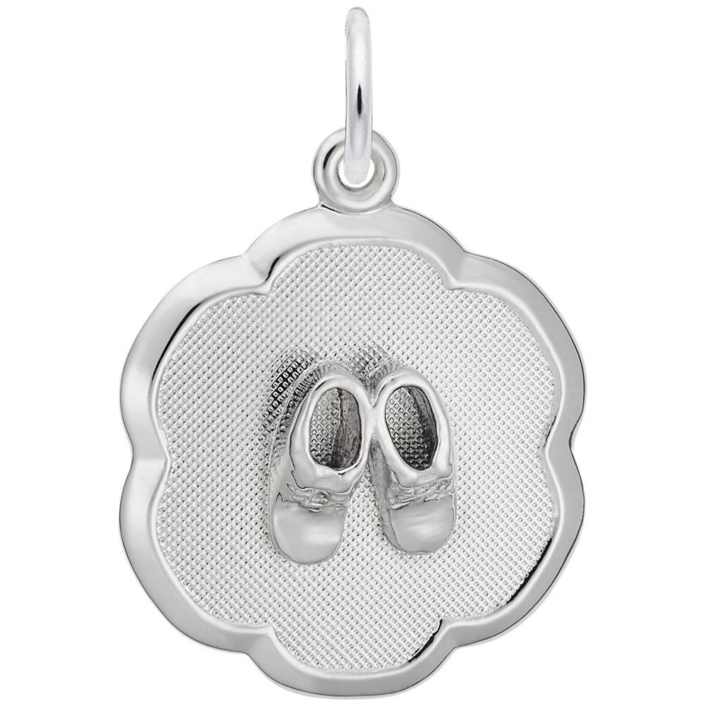 The image shows the Sterling Silver Baby Booties on Scalloped Disc Charm from Rembrandt Charms. The charm is crafted in sterling silver and features a pair of detailed baby booties set on a scalloped disc. It measures 0.69 inches by 0.69 inches (17.6 mm x 17.6 mm) and has the style number 0945. This charm is a perfect keepsake for commemorating a baby's early days.