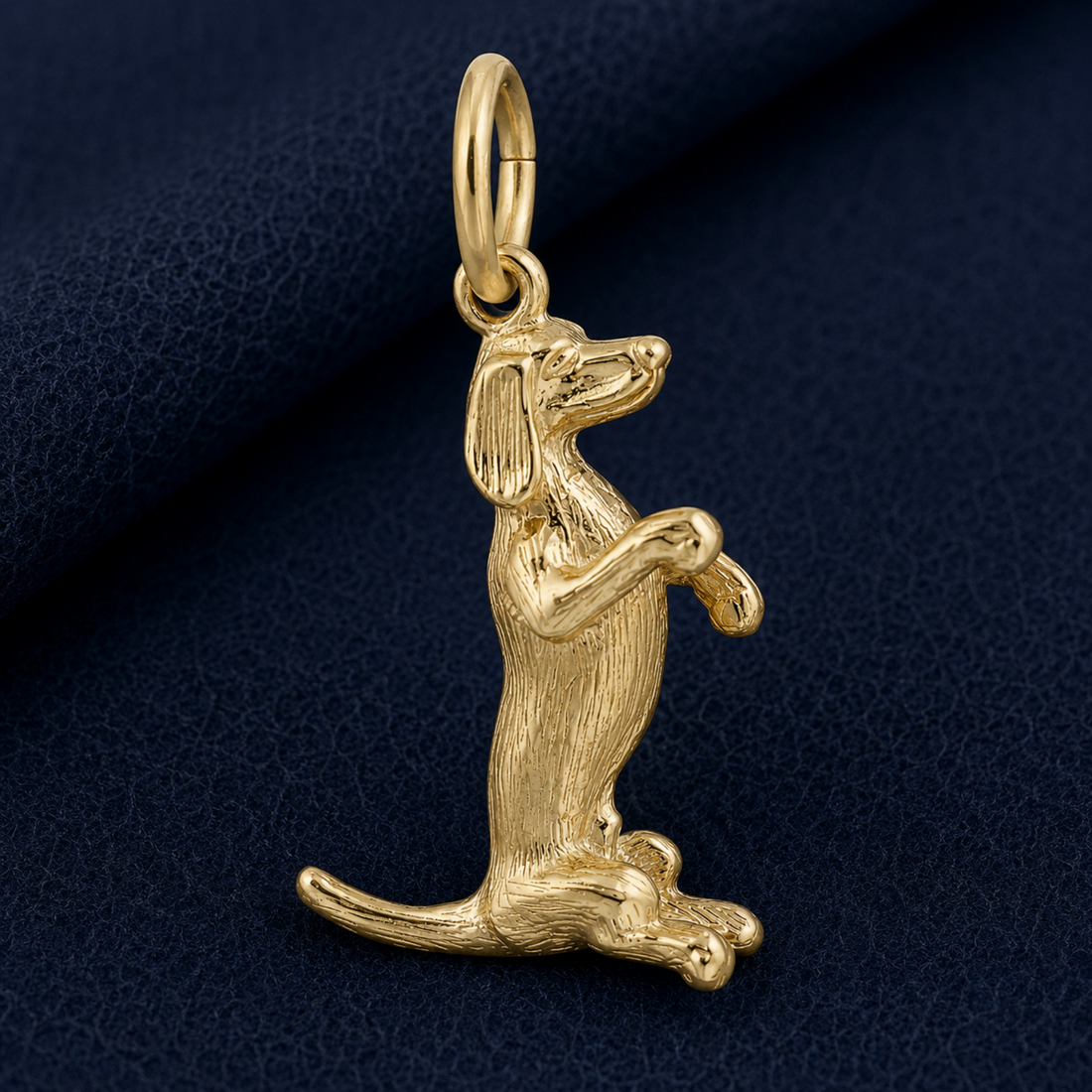 A Sitting Dachshund Charm in sterling silver by Rembrandt Charms, featuring detailed fur texture and crafted in the shape of a dog sitting upright on its hind legs, displayed against a dark blue textured background.