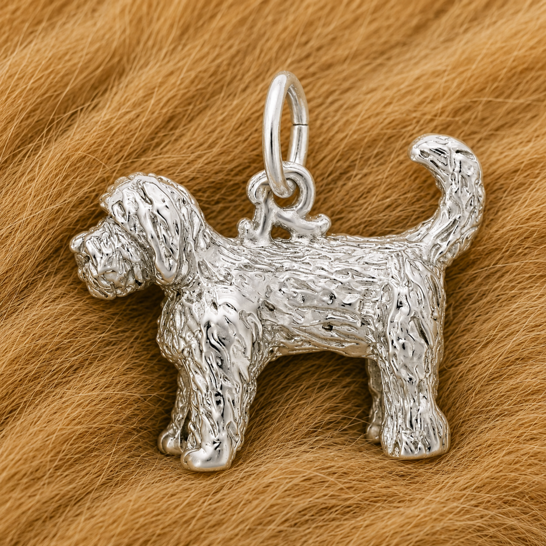 The Rembrandt Charms Labradoodle - Sterling Silver Charm, featuring intricate textured fur detail, rests on a soft light brown furry surface—the perfect gift for dog lovers.