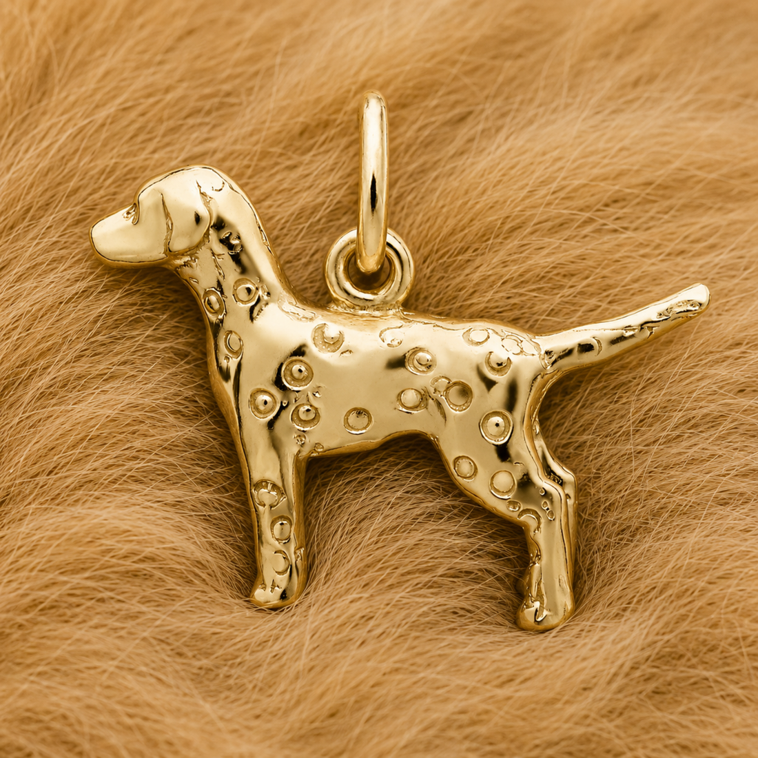 A Dalmatian Dog Charm by Rembrandt Charms, crafted in sterling silver and shaped like a spotted pup, stands on a soft, light brown furry background. This three-dimensional charm features a loop at the top for attaching to a chain or bracelet, making it the perfect piece of Dalmatian jewelry.