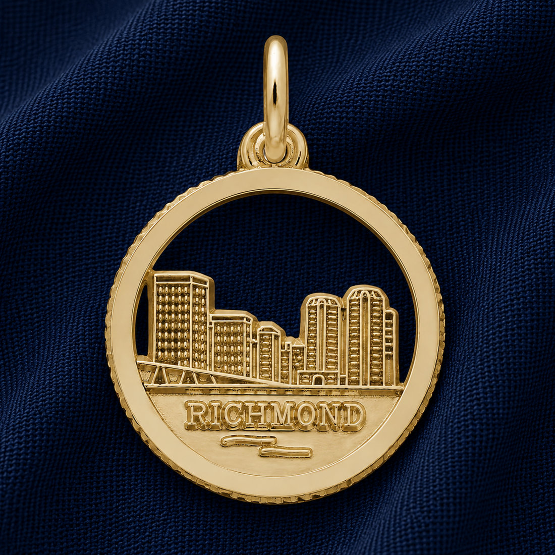 A sterling silver charm featuring a cutout of Kansas City’s skyline and the word “Kansas City,” from Rembrandt Charms, resting on dark blue fabric, makes a perfect travel keepsake or a unique addition to your charm bracelet.