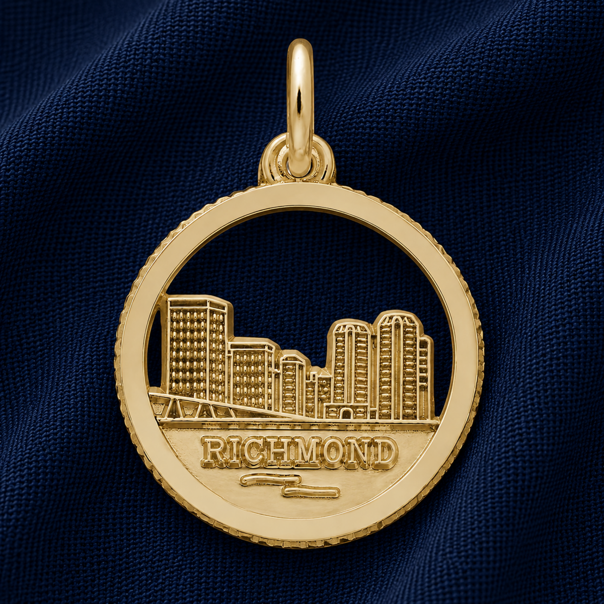 A sterling silver charm featuring a cutout of Kansas City’s skyline and the word “Kansas City,” from Rembrandt Charms, resting on dark blue fabric, makes a perfect travel keepsake or a unique addition to your charm bracelet.