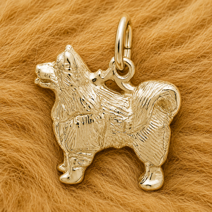 The Rembrandt Charms Samoyed Dog Charm—crafted from sterling silver to capture the fluffy elegance of the beloved breed—rests on a soft, light brown fur background, making it a perfect addition to any dog lover’s jewelry collection.