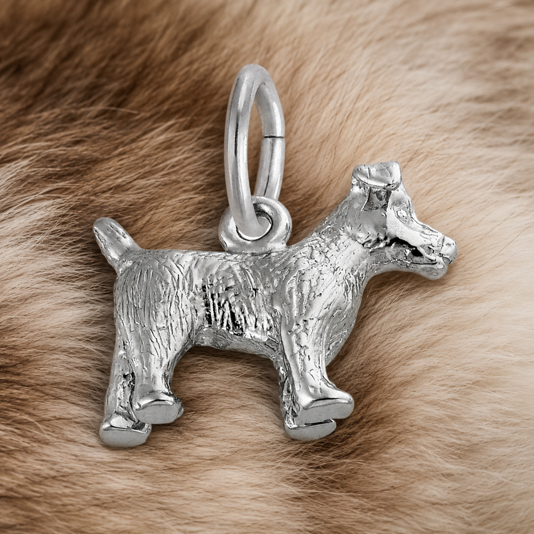 A Rembrandt Charms Jack Russell Terrier Charm in sterling silver is displayed on a soft, light brown and cream fur background, making it a delightful gift for any dog lover.