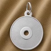 A round, sterling silver CD Charm by Rembrandt Charms—featuring a textured, radiating pattern and central hole reminiscent of a compact disc—rests elegantly on a brown textured fabric. This necklace is the perfect gift for music lovers.