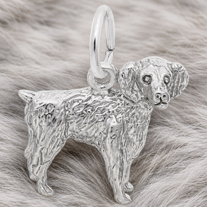 A gold-plated Boykin Spaniel Charm by Rembrandt Charms, featuring detailed fur texture and displayed on a soft, light gray fur background—a perfect jewelry piece for dog lovers inspired by South Carolina’s beloved state dog.