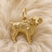 The Boykin Spaniel Charm—Gold Plated by Rembrandt Charms, inspired by South Carolina’s beloved state dog and detailed with curly fur, rests on a soft, light beige, fluffy surface—making it a perfect addition to any dog lover’s jewelry collection.