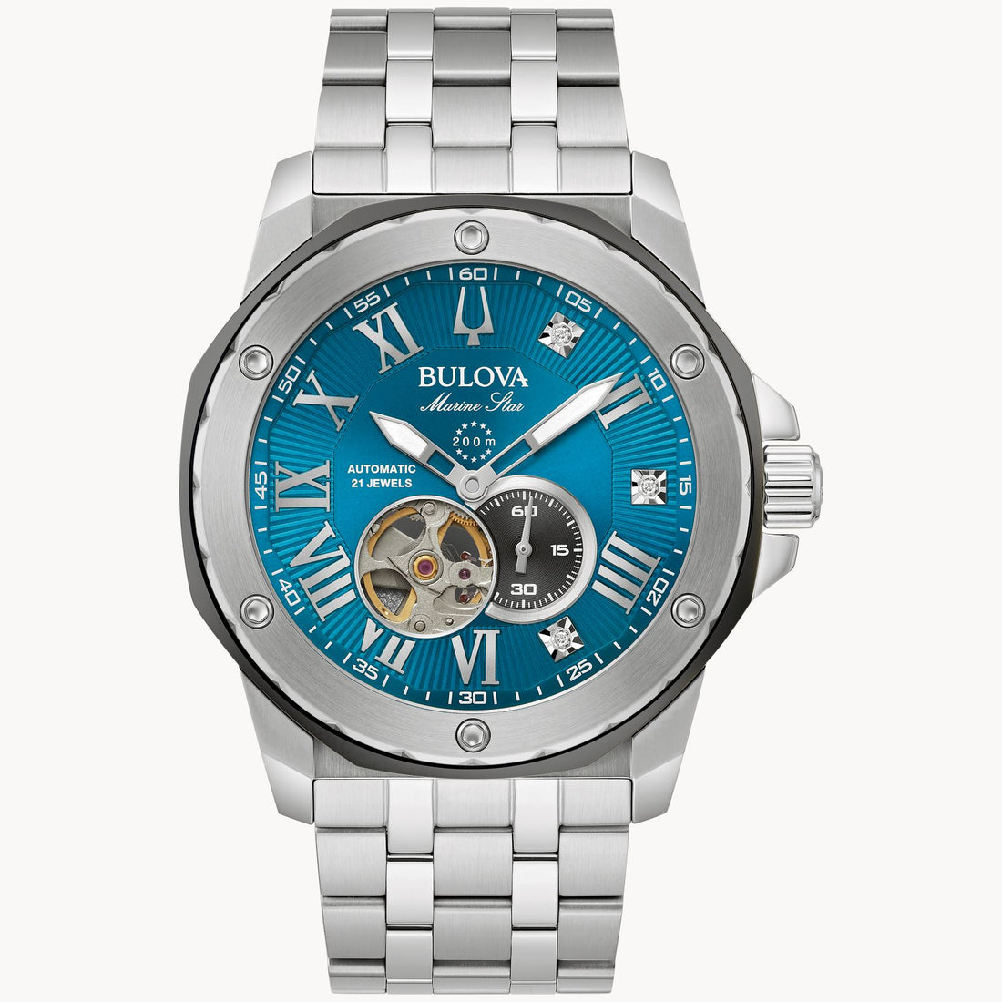 A Bulova Watch Company's Marc Anthony Blue Dial Automatic Watch with a stainless steel band. The watch features Roman numerals, diamond hour markers, a small window showing the inner mechanics, a date sub-dial, and luminous hands.