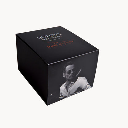 A black rectangular Bulova Watch Company box with “Bold at Heart” and “by Marc Anthony” on the lid, plus a grayscale man-in-sunglasses photo—perfect for gifting your Bulova Marc Anthony Marine Star White Dial Women's Watch.
