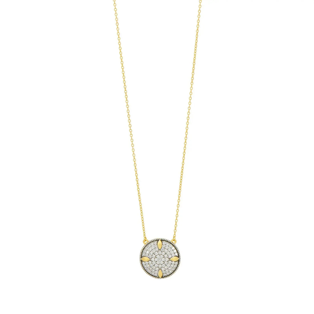 The Freida Rothman Petals and Pavé Small Pendant Necklace is a gold piece with a circular pendant displaying a star-like design embellished with diamonds, featuring intricate detailing akin to petals and pavé, suspended from a delicate chain.