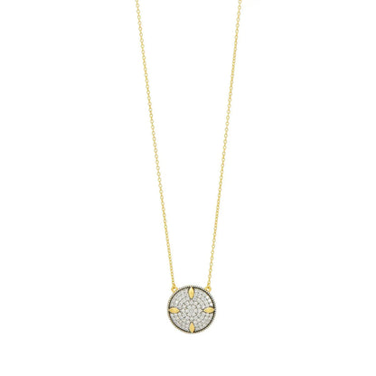 The Freida Rothman Petals and Pavé Small Pendant Necklace is a gold piece with a circular pendant displaying a star-like design embellished with diamonds, featuring intricate detailing akin to petals and pavé, suspended from a delicate chain.