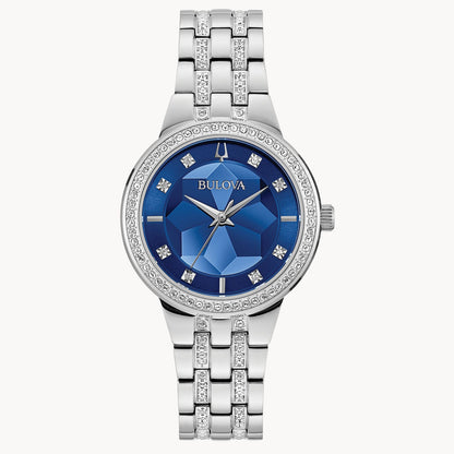 The Bulova Watch Company CRYSTAL L W BR BL C120 features a metallic band, blue faceted dial, crystal hour markers, and a sparkling crystal-encrusted bezel—radiating chandelier-like elegance with three silver hands and a polished design.