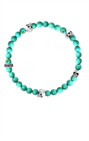 King Baby's 6mm turquoise bead bracelet showcases vibrant stones and is adorned with four striking silver skull accents.
