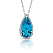 Description: The Magical Pear-Shaped Halo Necklace by Lafonn features a teardrop-shaped blue gemstone pendant encircled by a halo of Lassaire simulated diamonds, all set on a silver necklace chain. The radiant blue gem and twinkling diamonds create an eye-catching contrast. This timeless piece is beautifully reflected on the polished surface below.