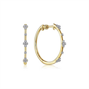 A pair of 14K Yellow Gold 20mm Round Classic Diamond Hoop Earrings from Gabriel & Co, featuring evenly spaced clusters of diamonds. One earring is shown in a side profile and the other in a front profile, highlighting their elegant design and sparkling embellishments against a white background.