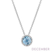 The Lafonn December Birthstone Necklace features a silver chain adorned with a round, light blue gemstone pendant surrounded by small clear crystals. The word "DECEMBER" is elegantly displayed in light purple text below the pendant.