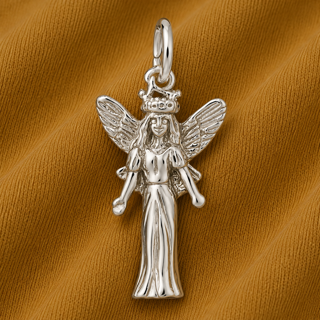 The Fairy—sterling silver charm by Rembrandt Charms features exquisite detailing and is beautifully displayed on a textured, golden-brown fabric background, making it an enchanting piece of whimsical jewelry.