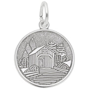 The Covered Bridge Disc Charm in Sterling Silver by Rembrandt Charms features an engraved design of a covered bridge encircled by trees. The textured background emphasizes the intricate scene, reflecting the artistry typical of Rembrandt Charms.