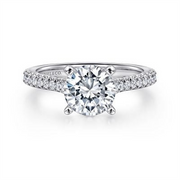 The 14K Gold Diamond Engagement Ring by Gabriel & Co features a large round-cut center in a four-prong setting, with smaller diamonds encrusted on the band, available in white gold or platinum for a sleek and elegant personalized masterpiece.
