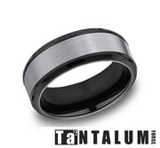 This sleek, metallic 8mm Tantalum and Black Titanium Satin Ring features a brushed silver center band and black edges. Below the ring, the word "Tantalum" is prominently displayed along with the number '73' and "FORGE." Crafted by Benchmark Rings, this Comfort-Fit design boasts a satin finish for a modern and sophisticated look.