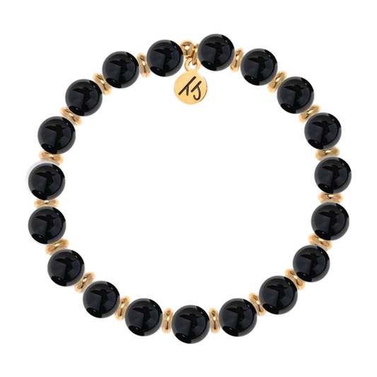 The T Jazelle Gold Empowered Elegance Collection- Onyx Gemstone Bracelet features alternating shiny black onyx beads, gold spacers, and a round gold charm engraved with "15.