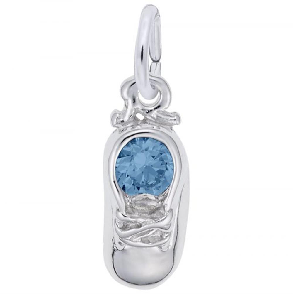 A sterling silver pendant in the shape of a baby shoe, adorned with a sparkling blue topaz birthstone on the upper part. The shoe features detailed laces and a small loop at the top for attaching to a chain or bracelet, making it the perfect Rembrandt Charms' December Baby Shoe Charm for any collection.