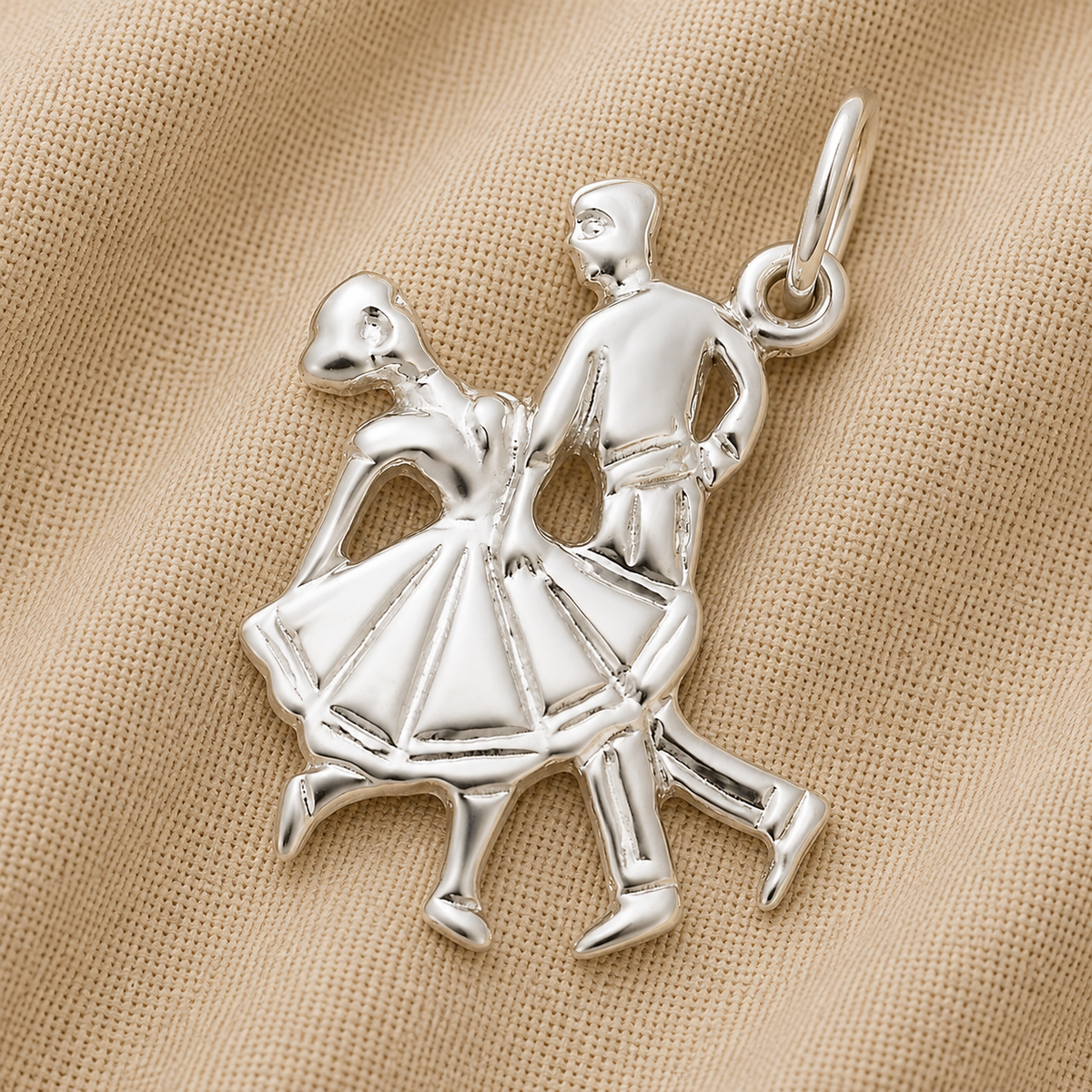 A beautiful Dancing Couple Charm in sterling silver from Rembrandt Charms, shaped like two dancers in mid-step and displayed on beige textured fabric—perfect for adding to your charm bracelet.