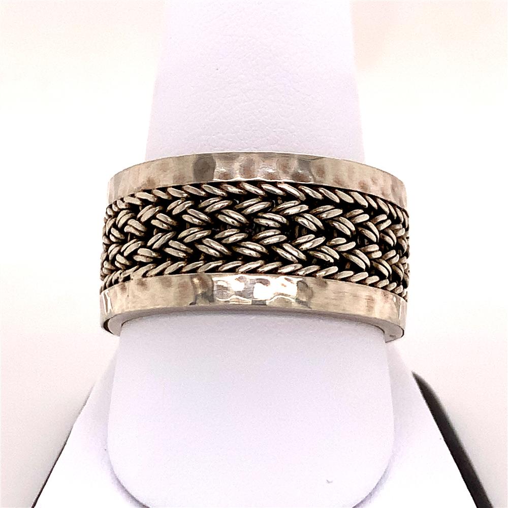A Lois Hill Gents Sterling Silver Ring / S, featuring a textured, hammered finish and a central woven design, elegantly displayed on a white ring stand.