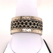 A Lois Hill Gents Sterling Silver Ring / S, featuring a textured, hammered finish and a central woven design, elegantly displayed on a white ring stand.