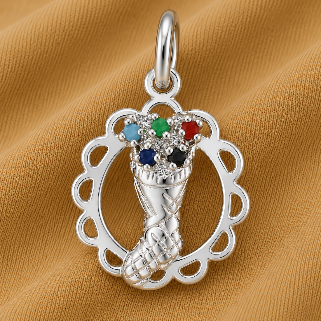 The Christmas Stocking Charm in sterling silver by Rembrandt Charms features festive red, green, blue, and turquoise accents and is displayed on a tan fabric background—making it the perfect holiday keepsake for fans of seasonal jewelry.
