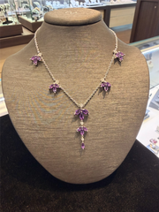 The Ryan Gems Floral Station Amethyst Necklace features multiple purple gemstones set in 18k white gold, elegantly displayed on a brown jewelry bust.