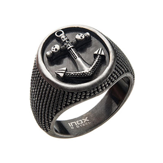The INOX Men's Stainless Steel Antique Finished Signet Ring features a silver-toned, round face with an intricately engraved anchor and skull design. The anchor has a rustic, distressed finish, and the band is textured with a rugged pattern. The inside of the ring is stamped with "INOX" and "STEEL," adding to its vintage appeal.