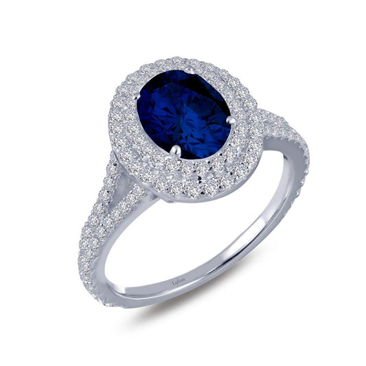 The Double-Halo Engagement Ring by Lafonn features a striking oval-shaped blue sapphire encircled by two halos of small white diamonds. The luxurious design is further enhanced with additional white diamonds encrusted along the band, creating an exquisite and dazzling effect.