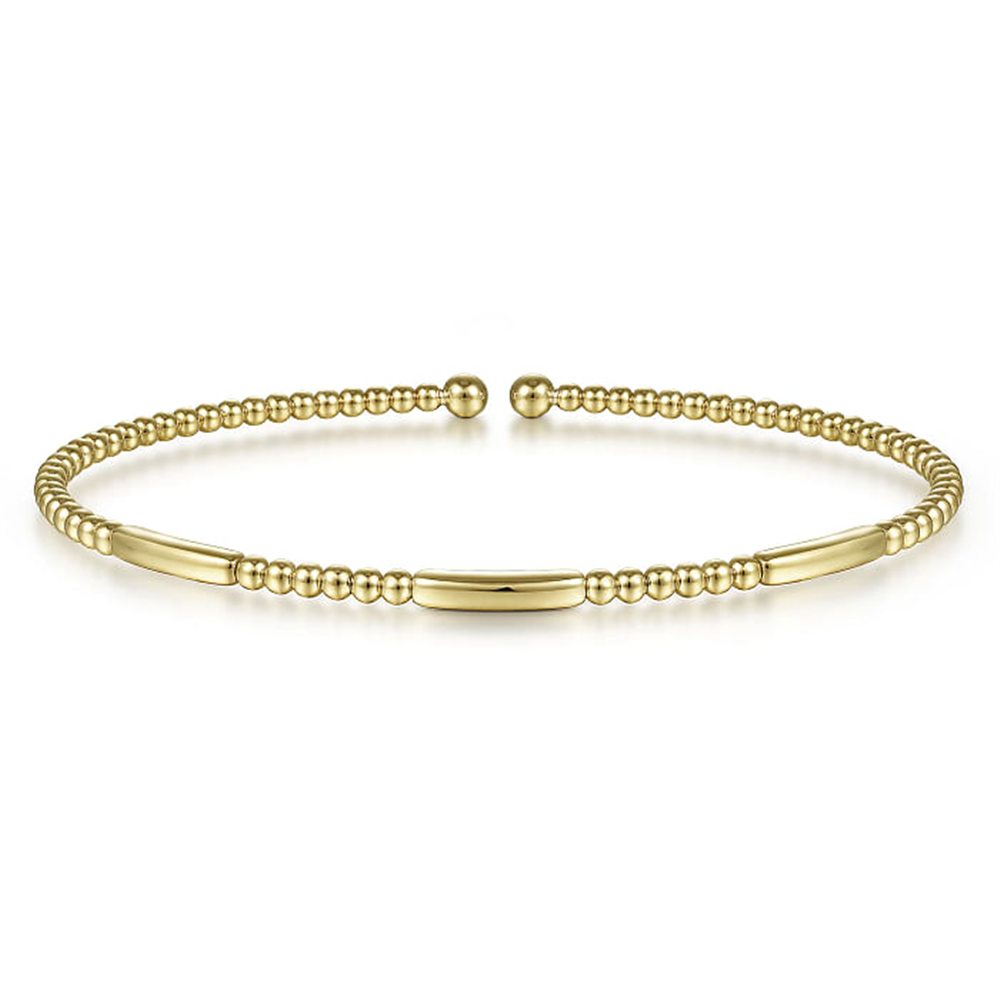 This 14K Yellow Gold Bujukan Open Bangle from Gabriel & Co features a slim, open design with small round gold beads alternating with smooth, elongated gold bars. The ends are capped with slightly larger round beads, and it boasts a shiny, polished finish.