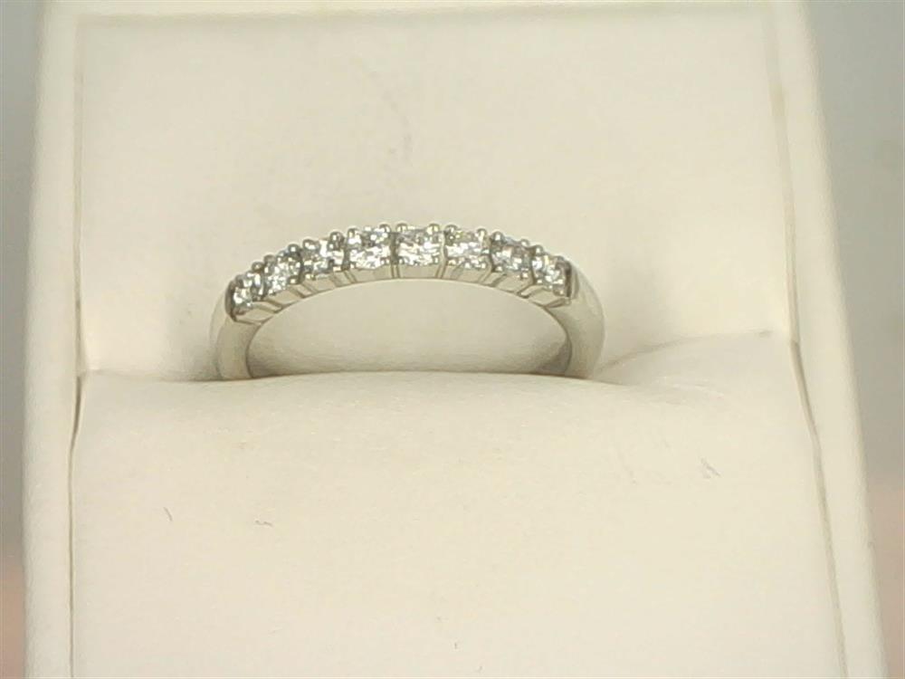 The 14K White Gold .32cts Round Cut Diamond Anniversary Band from Benchmark Rings is displayed in a white jewelry box. The anniversary band stands out against the soft white background, highlighting its elegant and simple design.