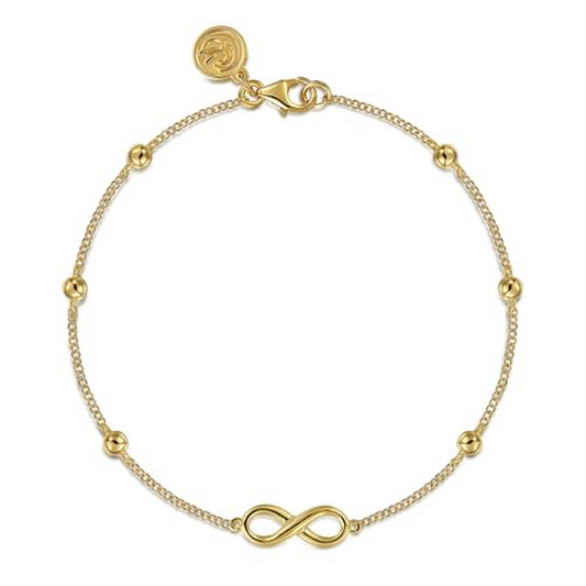 The Gabriel & Co 14k yellow gold Bujukan chain bracelet features an elegant infinity station, adorned with small gold beads and secured with a lobster clasp, complemented by a circular charm near the fastening.