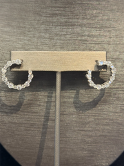 A pair of Ryan Gems Diamond Open Circle Earrings in 14k white gold is displayed on a metallic stand against a dark, textured background.