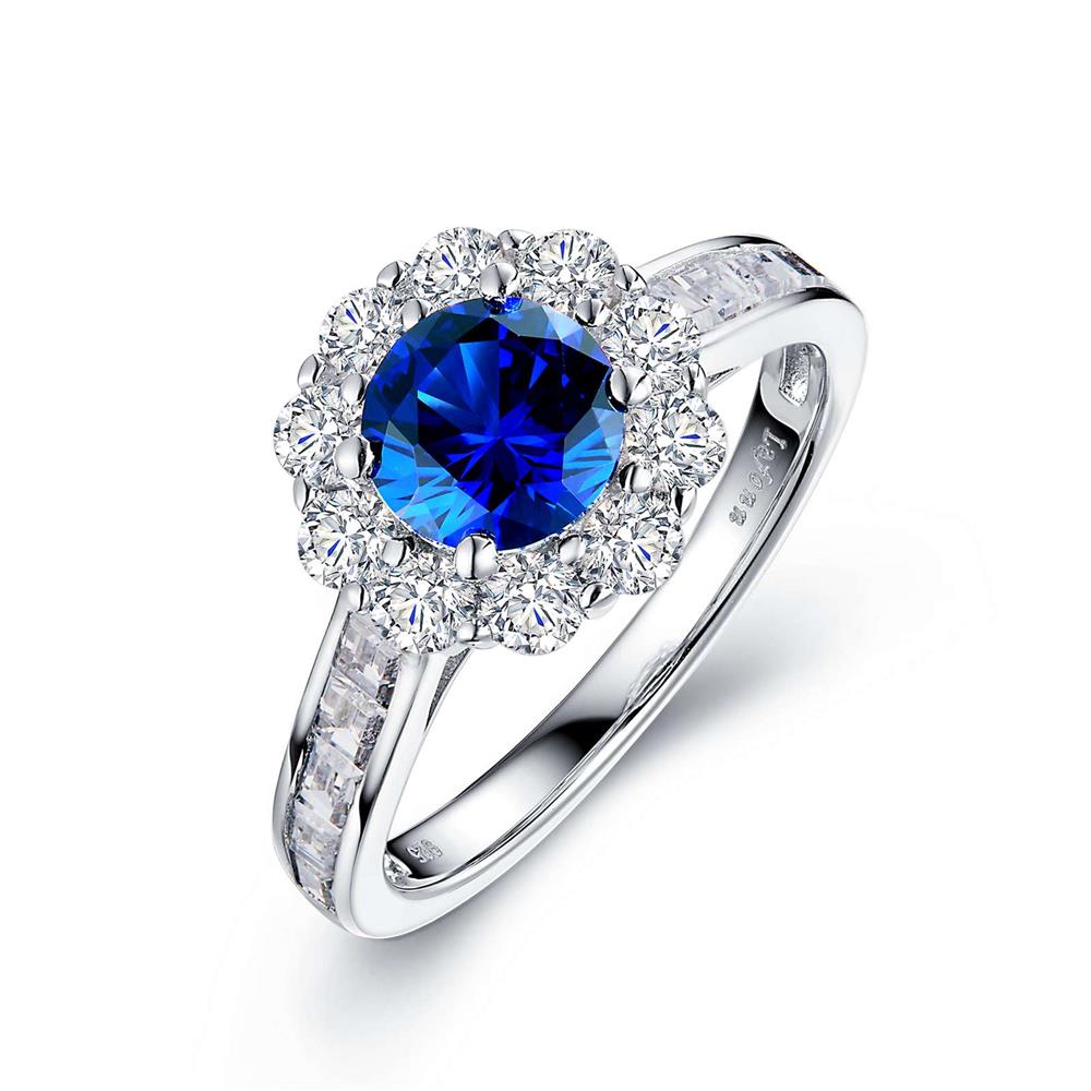 The Lafonn Sterling Silver Halo Engagement Ring features a striking design, showcasing a large, round blue gemstone at the center, surrounded by smaller white diamonds. The band is adorned with square-cut diamonds along the top, further enhancing its elegant and luxurious appeal.