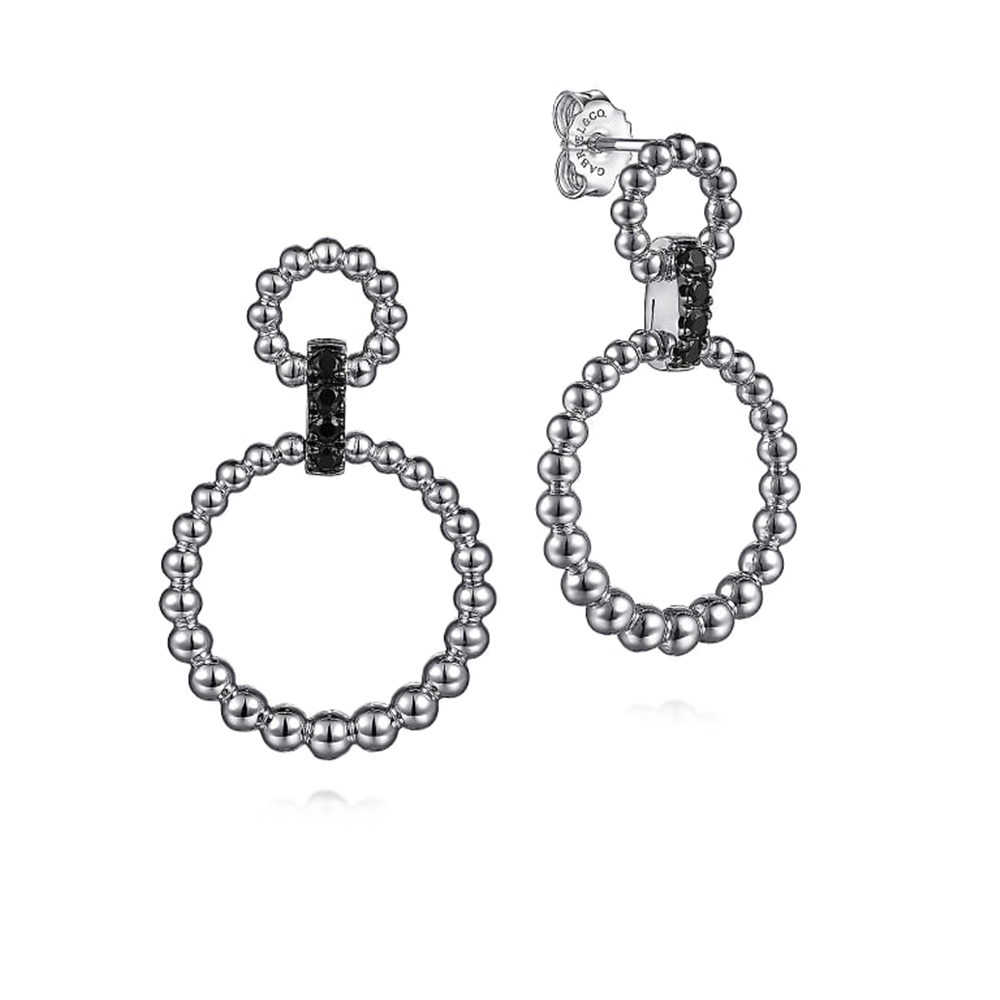 The Sterling Silver Black Spinel Bujukan Link Drop Earrings from Gabriel & Co feature interlocking circular designs made up of small, silver beads. Crafted in sterling silver, each earring has two connected circles with a smaller one atop a larger one, both adorned with black spinel accents and secured with a simple post back.